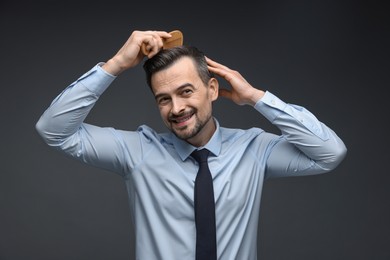 Photo of Handsome man combing his hair on dark background