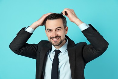 Handsome man stylish his hair with comb on light blue background