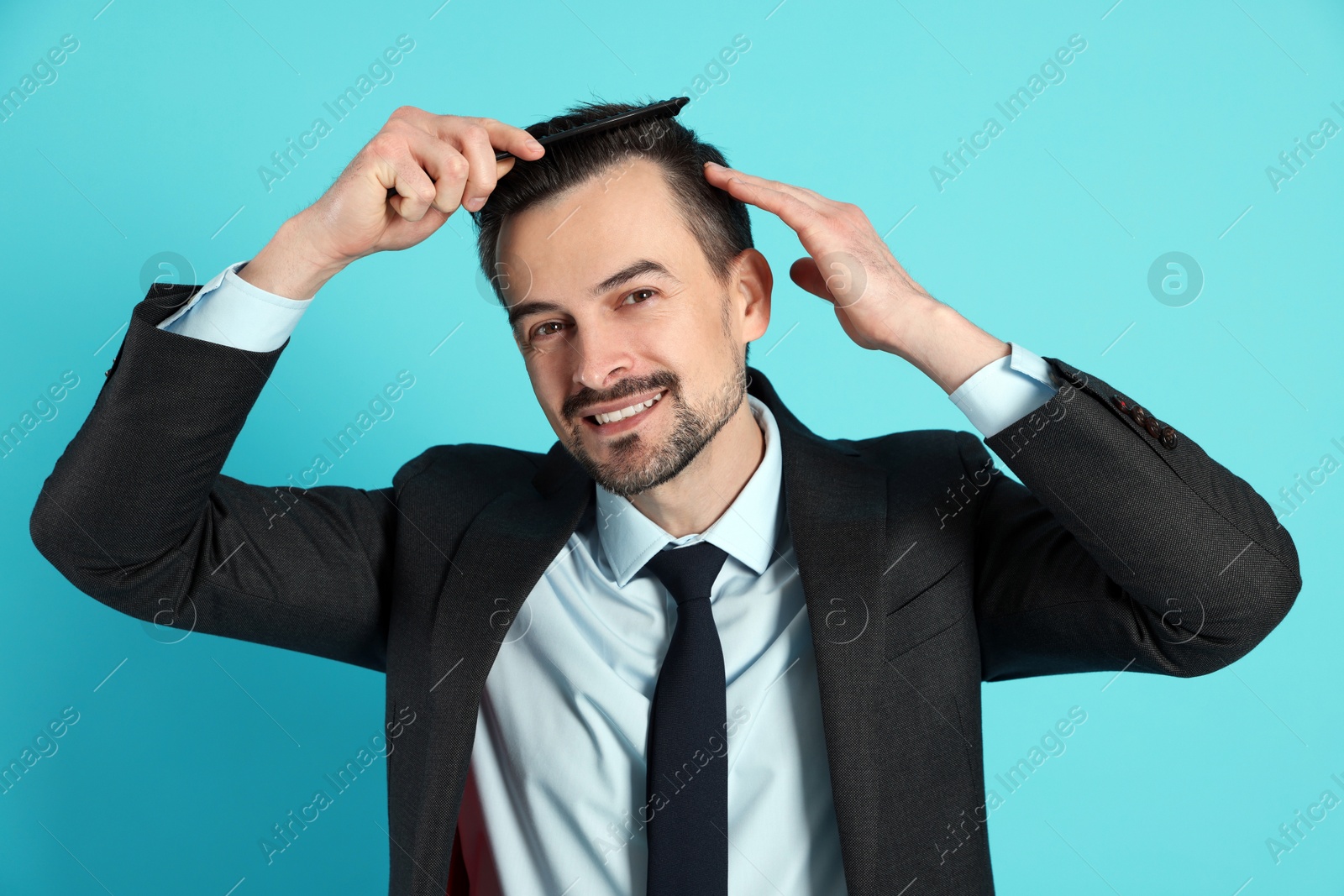 Photo of Handsome man stylish his hair with comb on light blue background