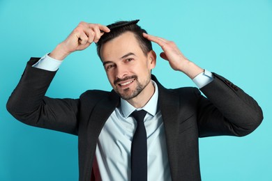 Photo of Handsome man stylish his hair with comb on light blue background