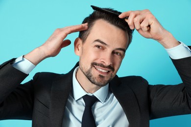 Photo of Handsome man stylish his hair with comb on light blue background