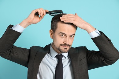 Photo of Handsome man stylish his hair with comb on light blue background