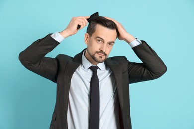 Photo of Handsome man stylish his hair with comb on light blue background