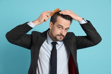 Photo of Handsome man stylish his hair with comb on light blue background