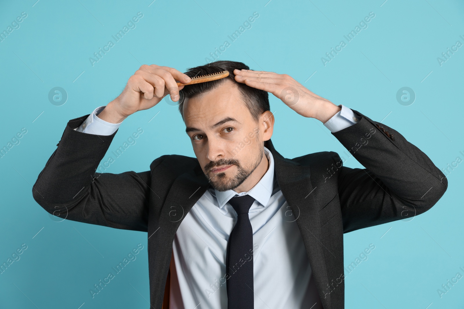 Photo of Handsome man stylish his hair with comb on light blue background