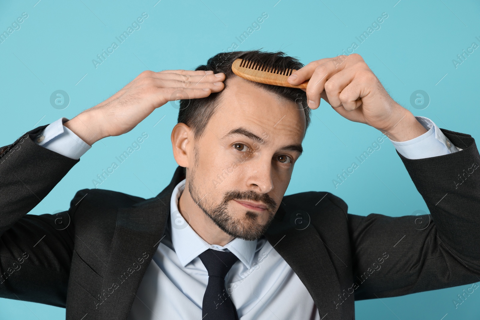 Photo of Handsome man stylish his hair with comb on light blue background