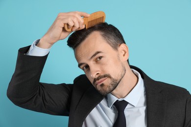 Photo of Handsome man stylish his hair with comb on light blue background