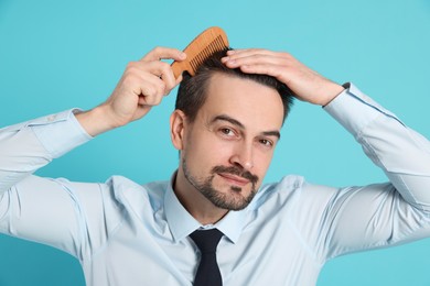 Photo of Handsome man stylish his hair with comb on light blue background