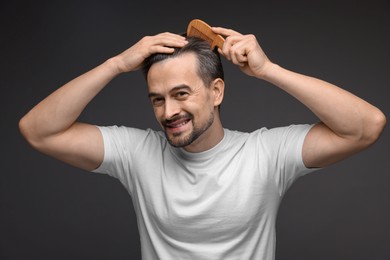 Photo of Handsome man combing his hair on dark background