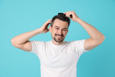 Photo of Handsome man stylish his hair with comb on light blue background