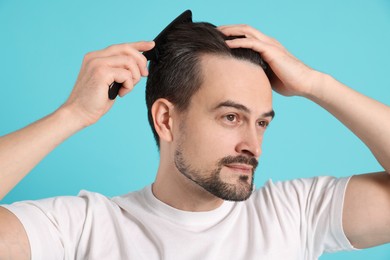 Photo of Handsome man stylish his hair with comb on light blue background