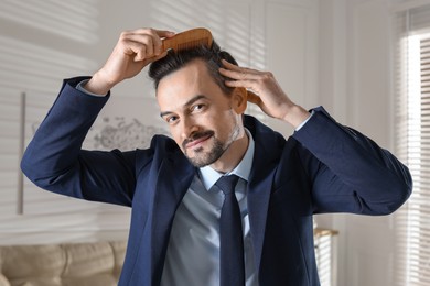 Photo of Handsome man combing his hair at home