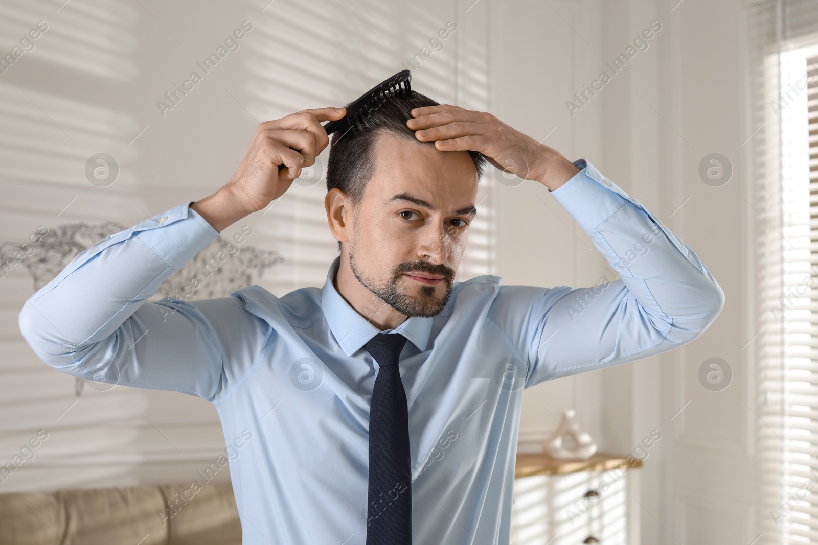 Photo of Handsome man combing his hair at home