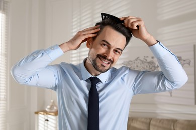 Photo of Handsome man combing his hair at home