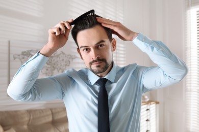 Photo of Handsome man combing his hair at home