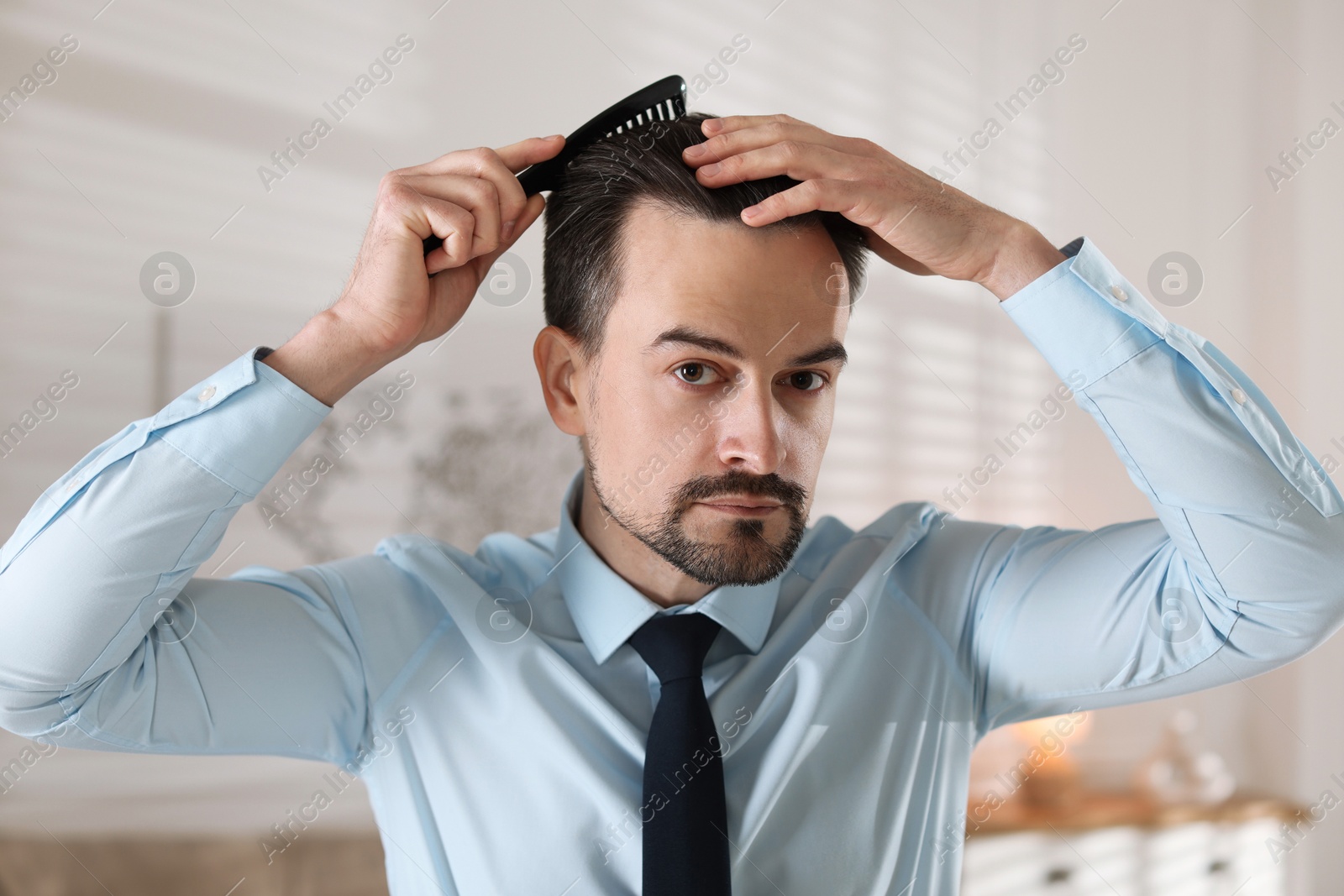 Photo of Handsome man combing his hair at home