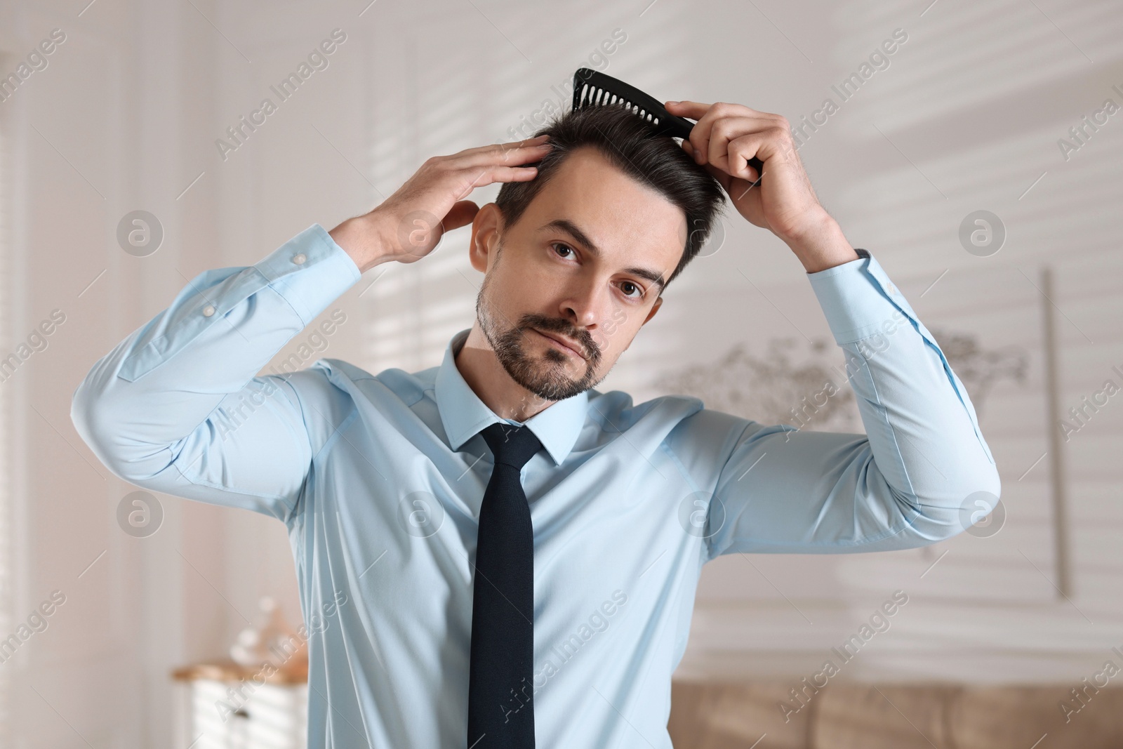 Photo of Handsome man combing his hair at home