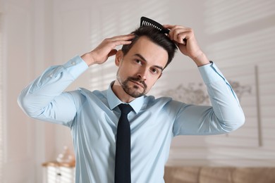 Photo of Handsome man combing his hair at home