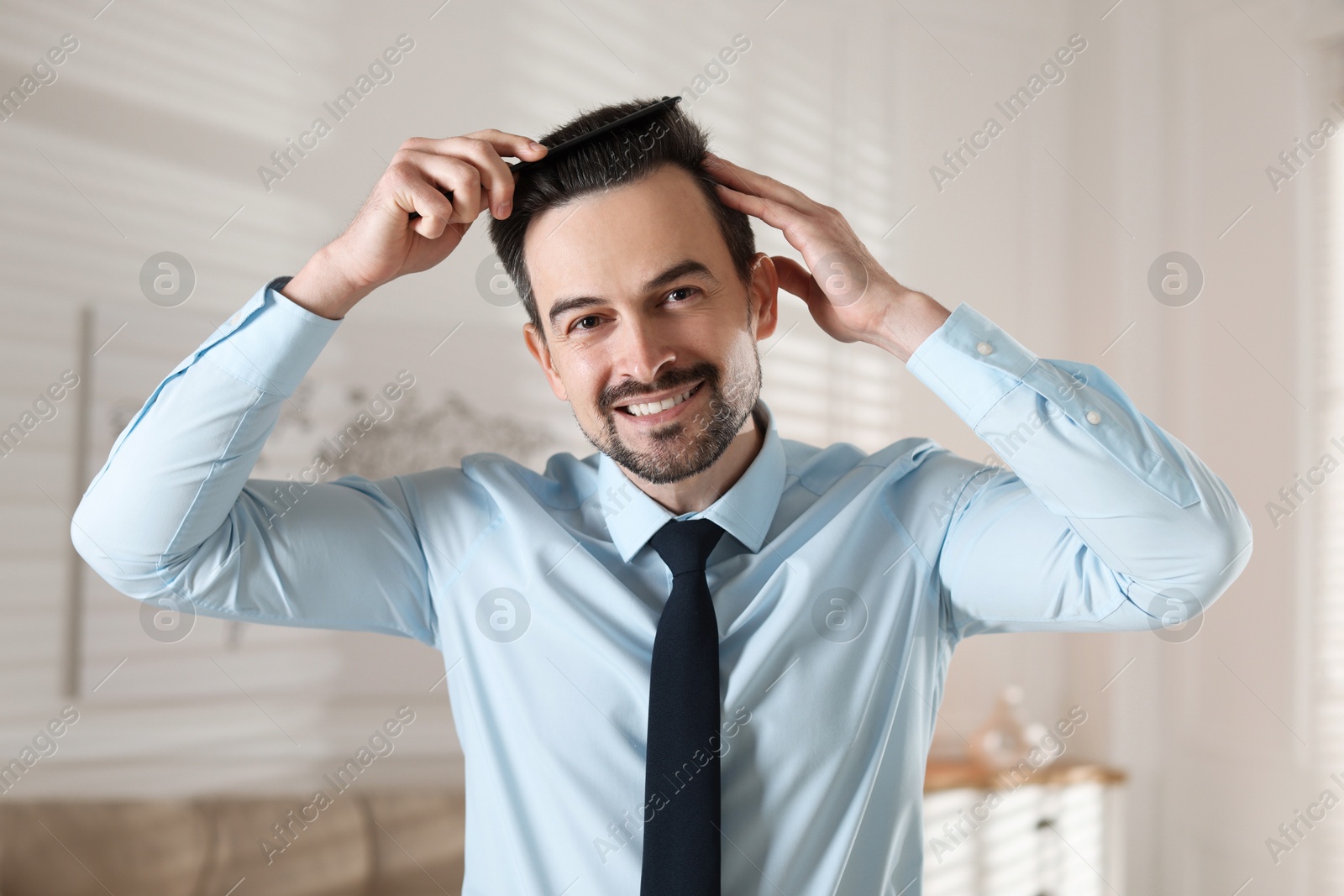 Photo of Handsome man combing his hair at home