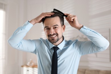 Handsome man combing his hair at home