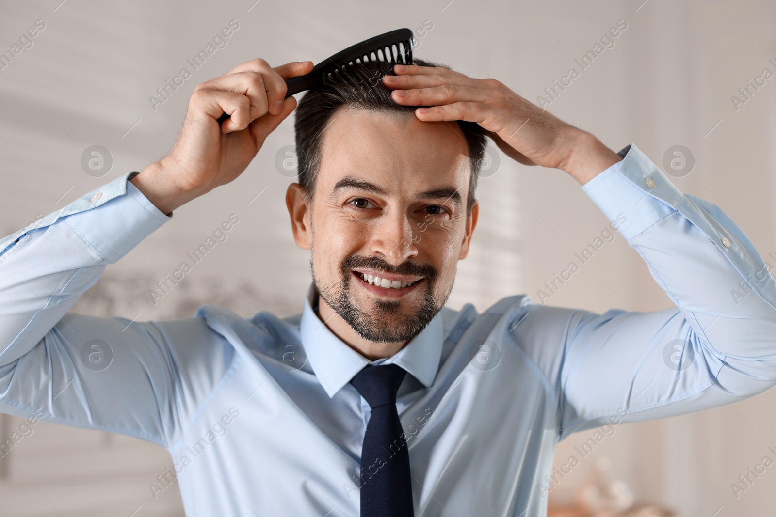 Photo of Handsome man combing his hair at home