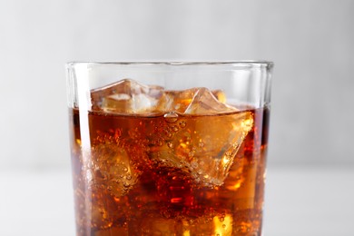 Photo of Sweet soda water with ice cubes in glass on blurred background, closeup