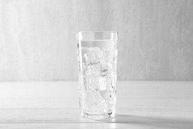 Photo of Refreshing soda water with ice cubes in glass on white wooden table