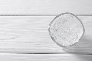 Photo of Refreshing soda water with ice cubes in glass on white wooden table, top view. Space for text