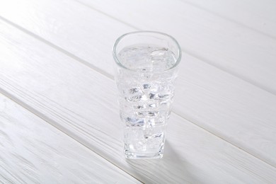 Photo of Refreshing soda water with ice cubes in glass on white wooden table