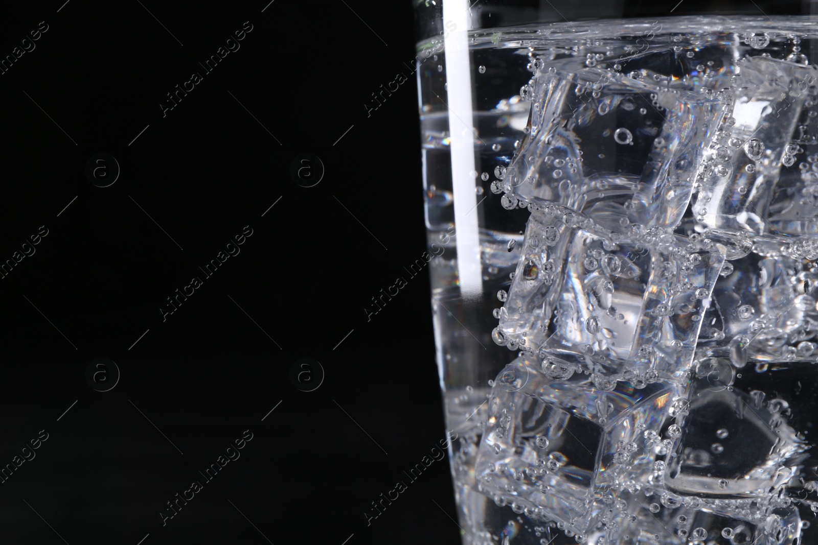 Photo of Refreshing soda water with ice cubes in glass on black background, closeup. Space for text