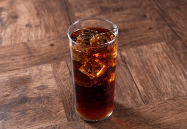 Photo of Sweet soda water with ice cubes in glass on wooden table