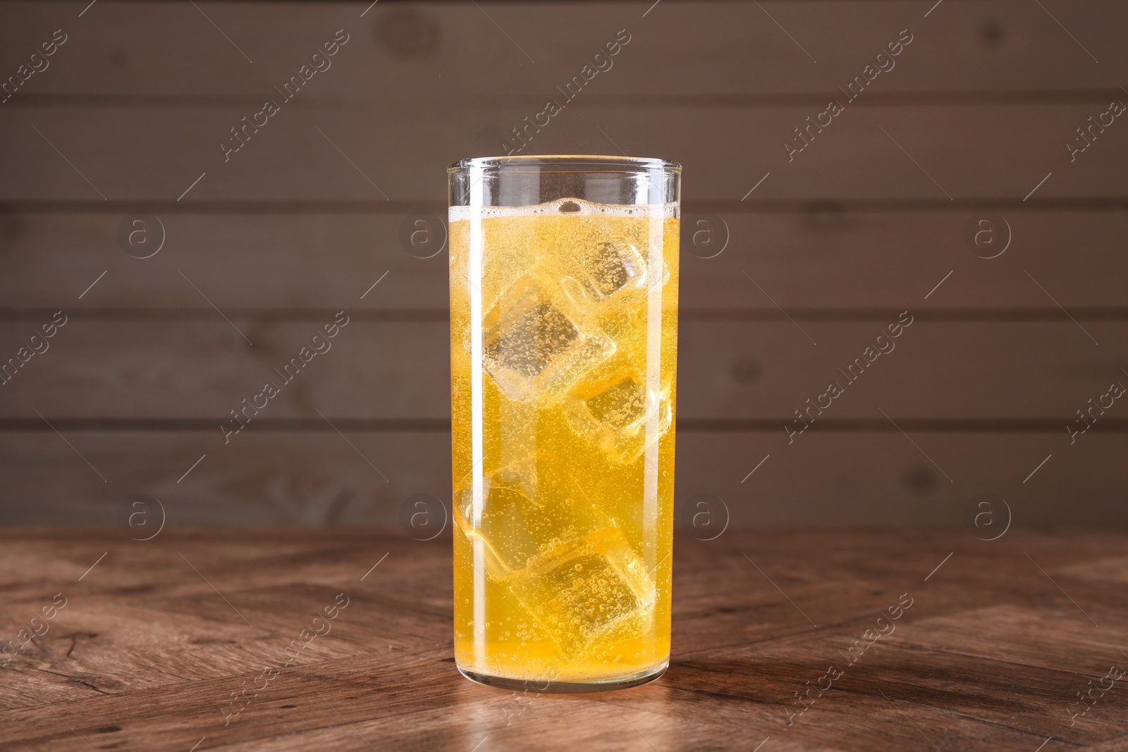 Photo of Sweet soda water with ice cubes in glass on wooden table