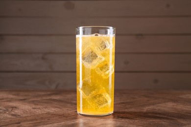 Photo of Sweet soda water with ice cubes in glass on wooden table