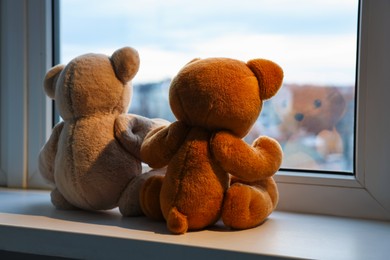 Photo of Two cute teddy bears near window indoors, back view