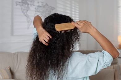 Photo of Woman brushing her curly hair at home