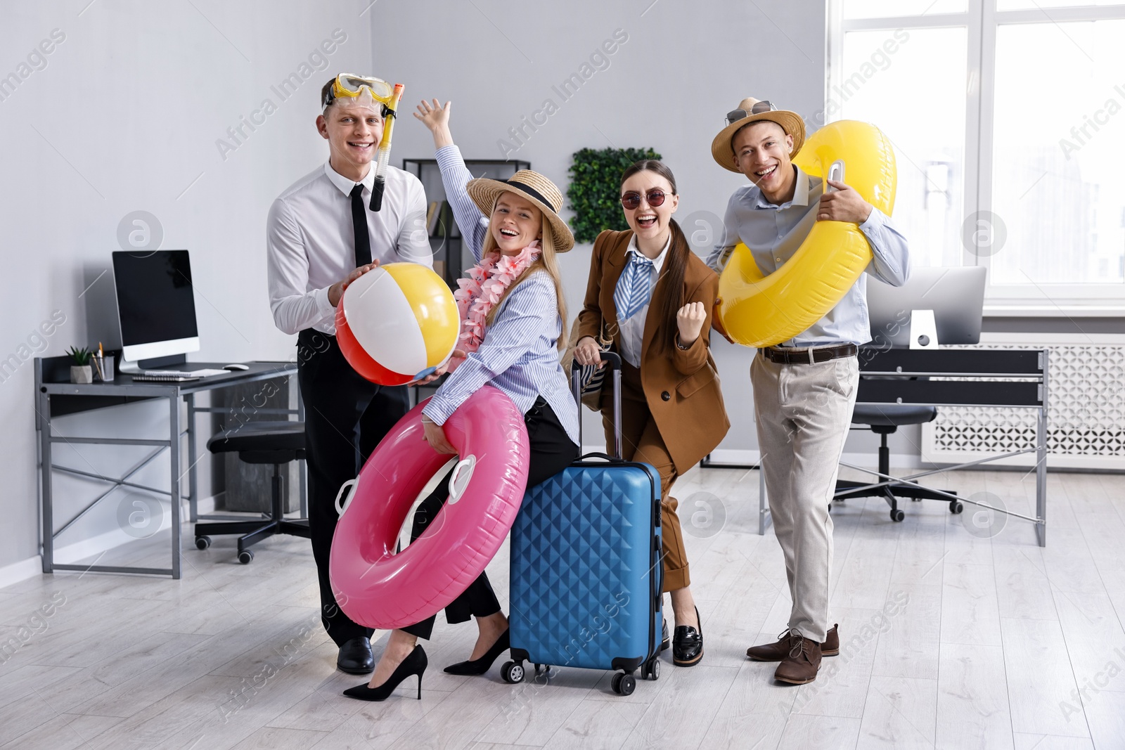 Photo of Colleagues with different beach accessories having fun in office