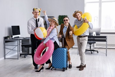 Photo of Colleagues with different beach accessories having fun in office