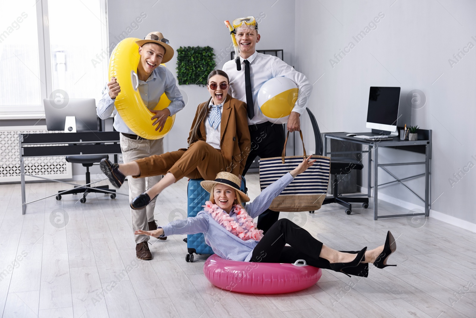 Photo of Colleagues with different beach accessories having fun in office