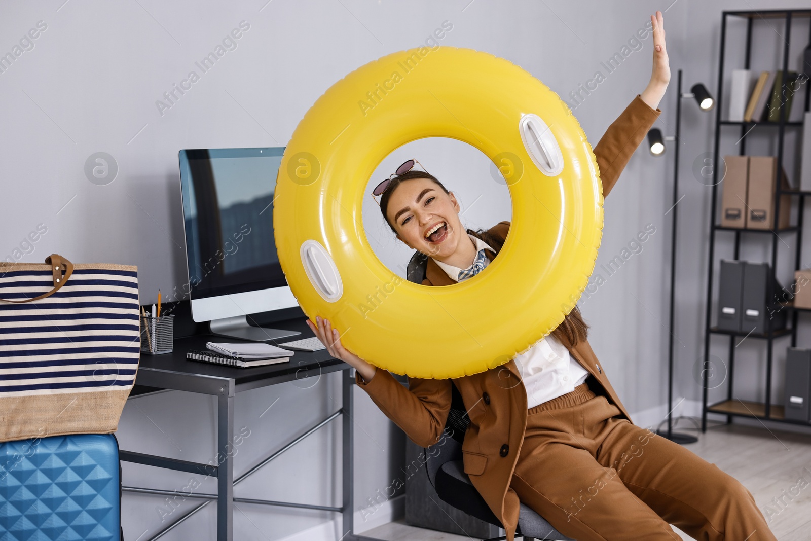 Photo of Businesswoman with inflatable ring and sunglasses at workplace in office