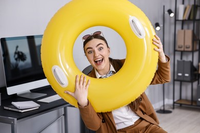 Photo of Businesswoman with inflatable ring and sunglasses at workplace in office