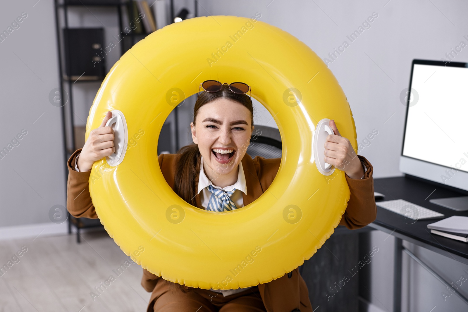 Photo of Businesswoman with inflatable ring and sunglasses at workplace in office