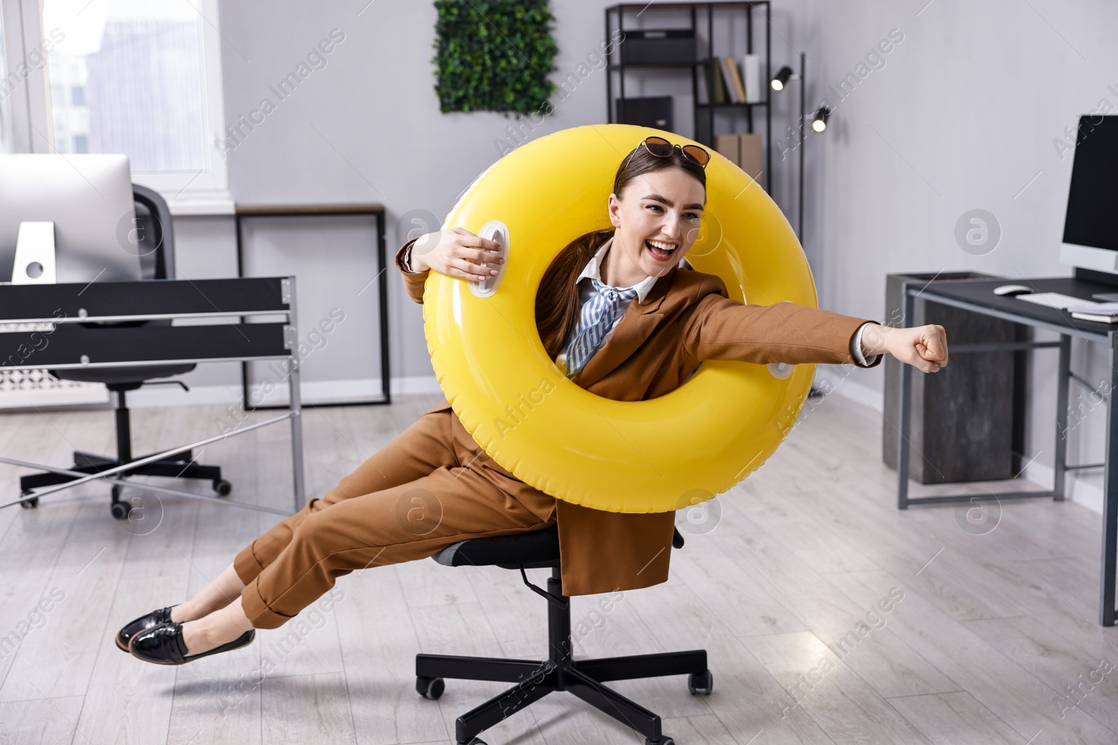 Photo of Businesswoman with inflatable ring and sunglasses posing on chair in office