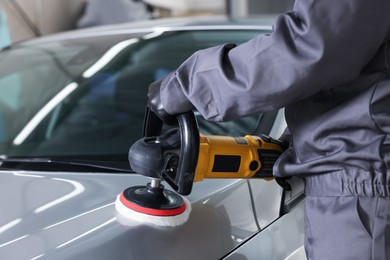 Photo of Man polishing car with orbital polisher indoors, closeup