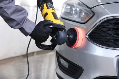 Photo of Man polishing car with orbital polisher indoors, closeup