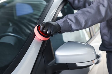 Photo of Man polishing car with sponge indoors, closeup