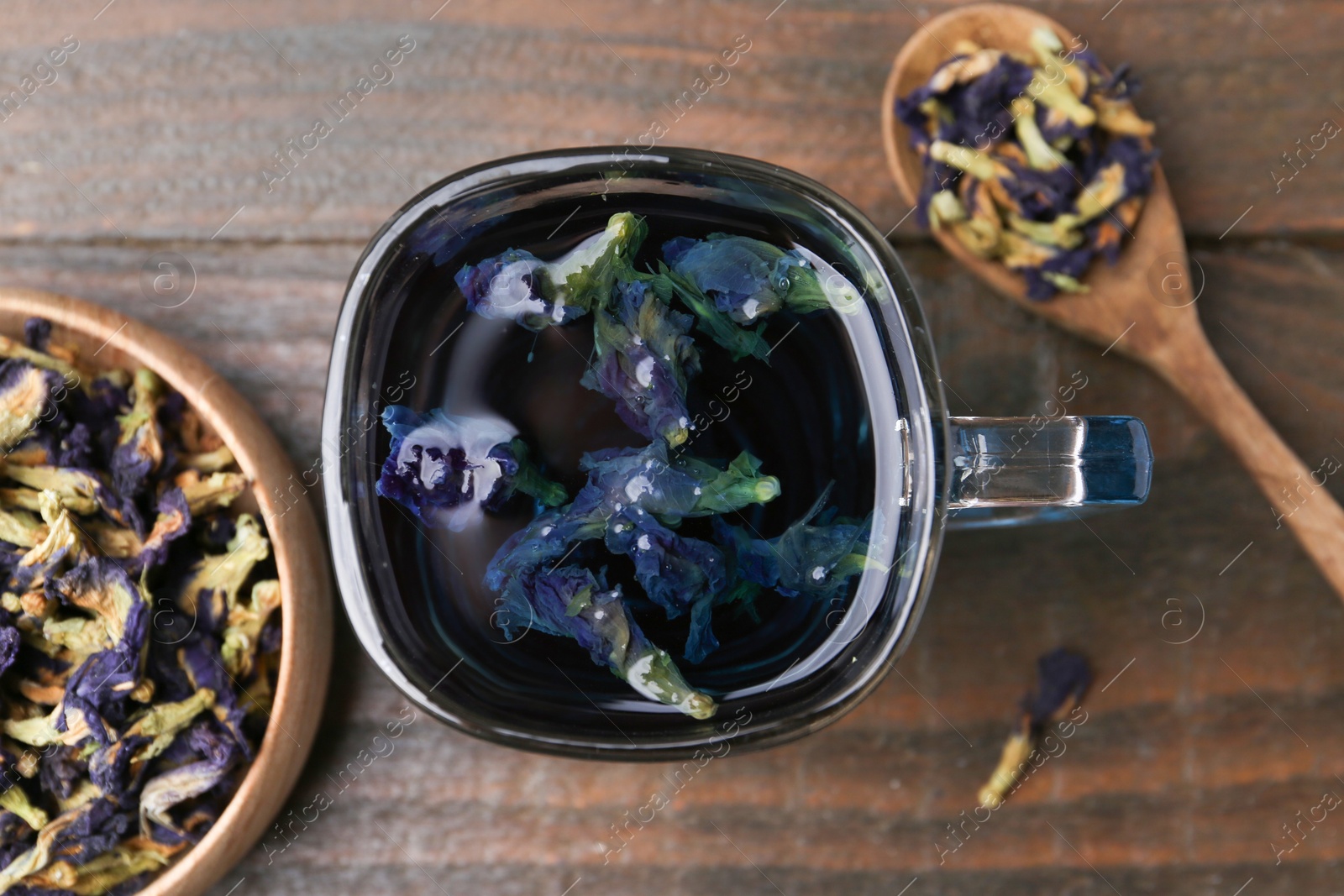 Photo of Delicious butterfly pea flower tea on wooden table, flat lay