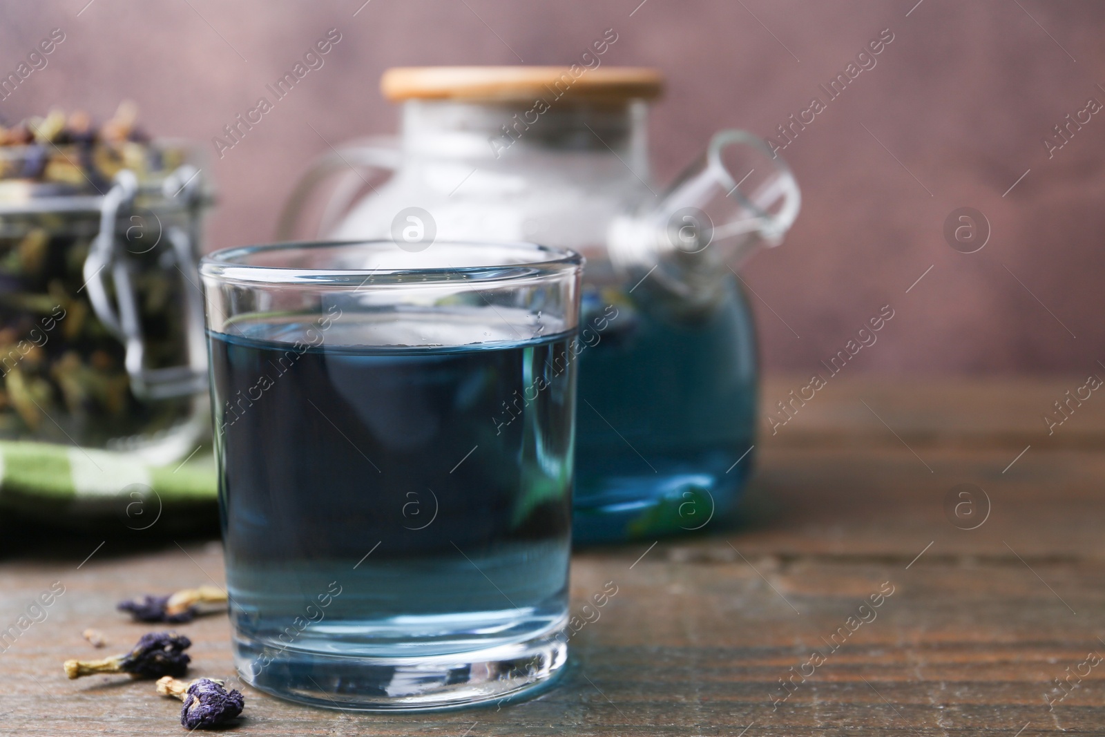 Photo of Delicious butterfly pea flower tea on wooden table against brown background. Space for text