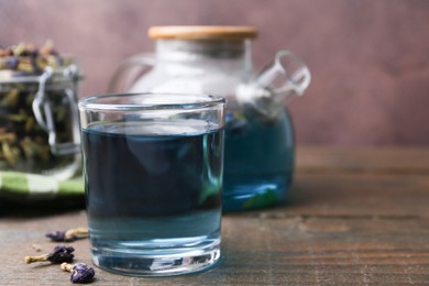 Photo of Delicious butterfly pea flower tea on wooden table against brown background. Space for text