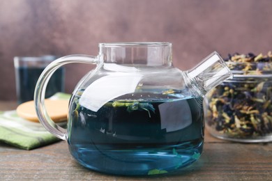 Photo of Delicious butterfly pea flower tea on wooden table against brown background