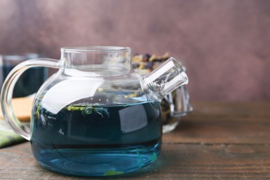 Delicious butterfly pea flower tea on wooden table against brown background. Space for text